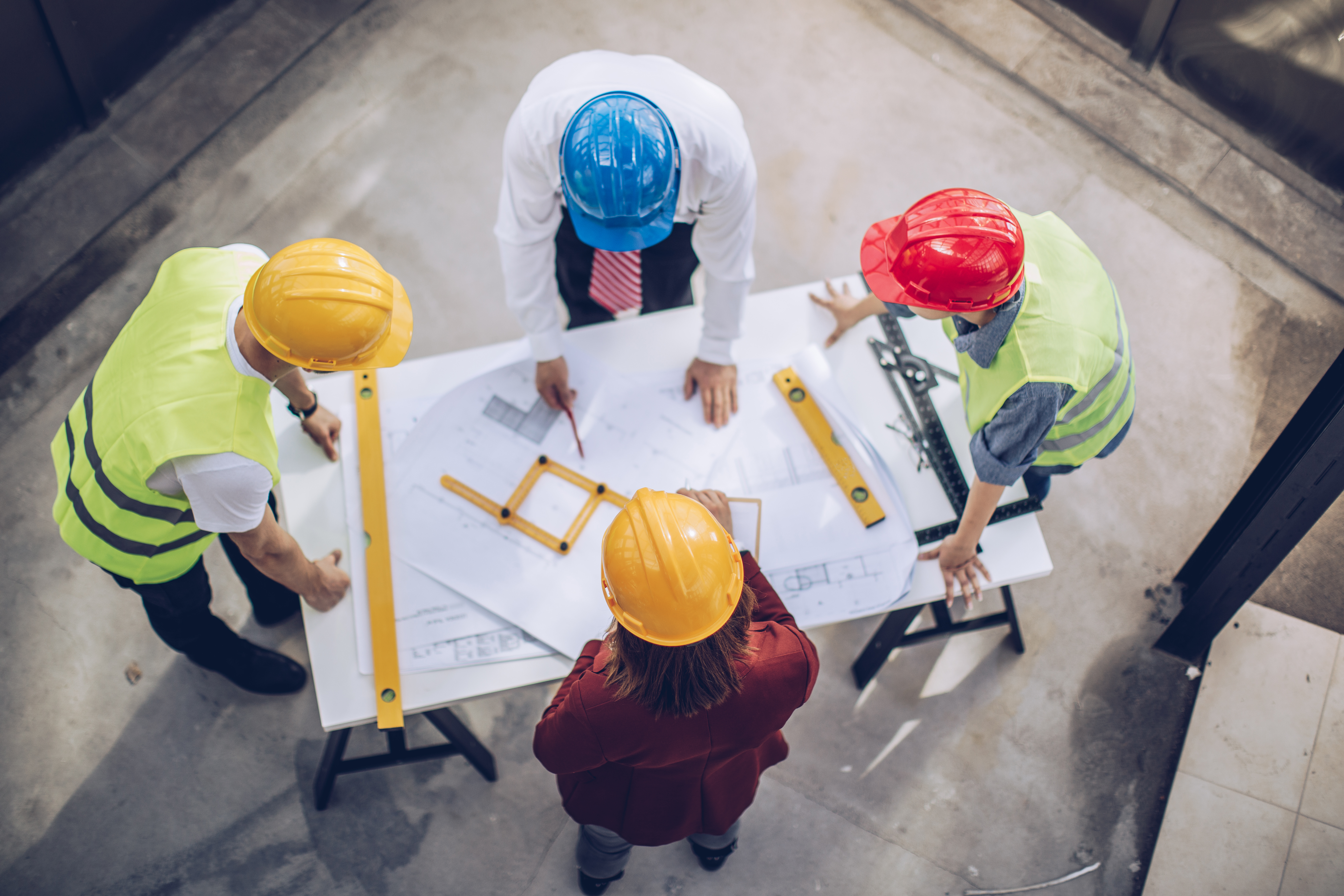 Image of fours contractors looking at blue prints at a construction site